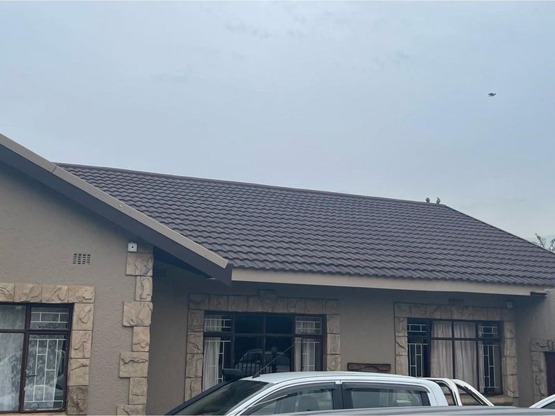 A view of the front facade of the house featuring a tiled roof, textured wall finish, and stone-cladding accents around the window frames.