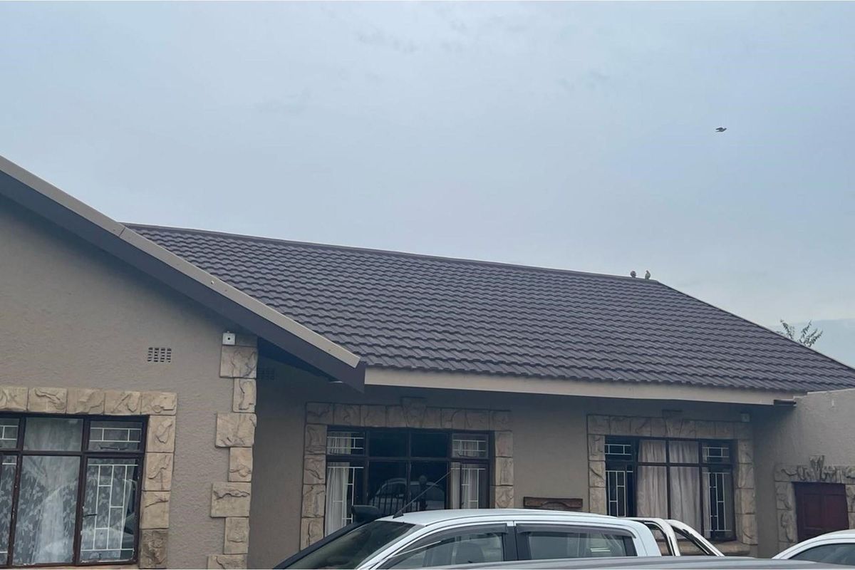 A view of the front facade of the house featuring a tiled roof, textured wall finish, and stone-cladding accents around the window frames.
