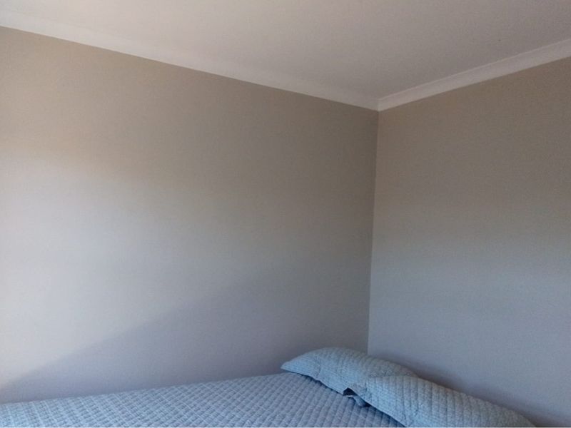 A simple bedroom corner featuring neutral painted walls and decorative ceiling coving.