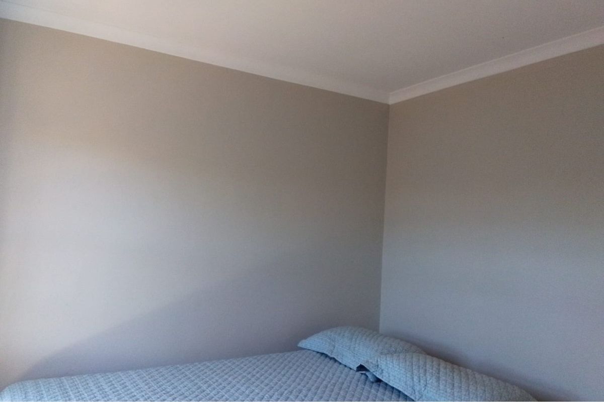 A simple bedroom corner featuring neutral painted walls and decorative ceiling coving.