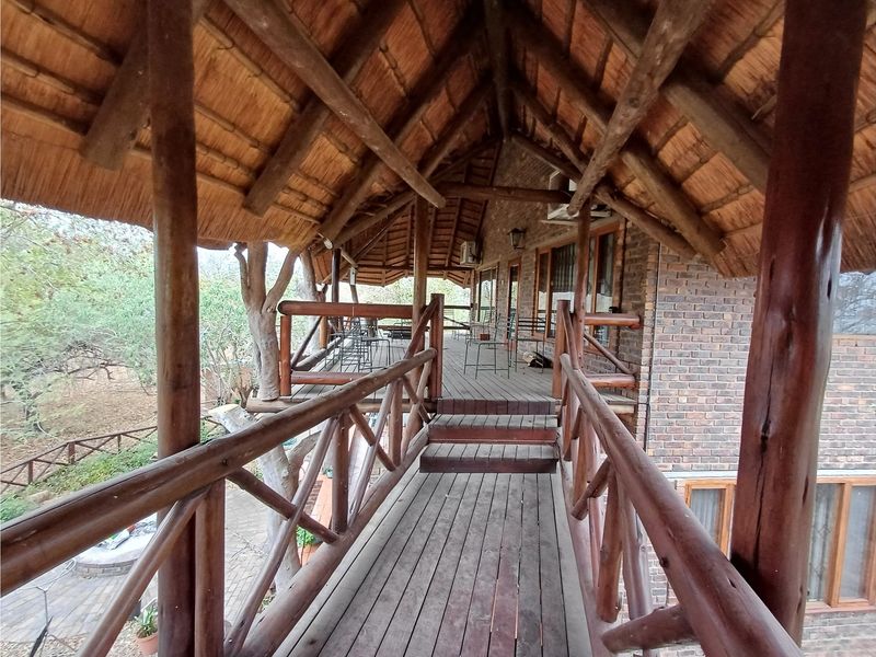 Elevated timber walkway and balcony featuring a traditional thatched roof, exposed timber rafters, and rustic brick walling overlooking the surrounding landscape.