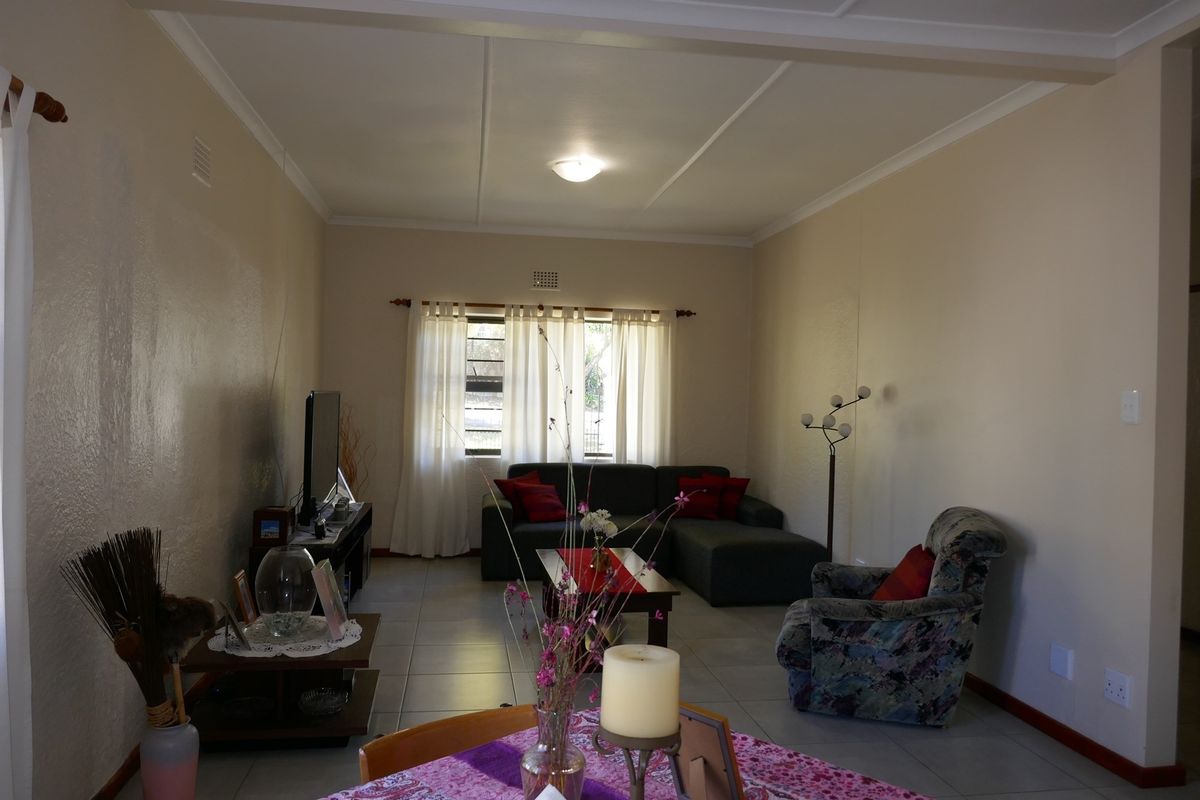 A functional living room featuring tiled flooring, neutral wall finishes, and a window with natural light.