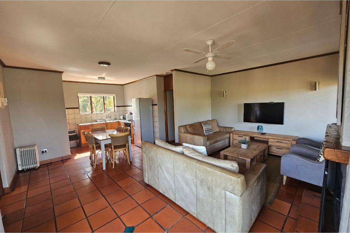 Open-plan living and kitchen area featuring terracotta floor tiles, a ceiling fan, and a functional kitchen layout.
