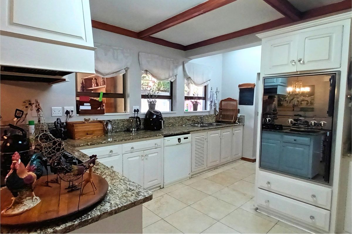 A functional kitchen featuring granite countertops, white cabinetry, integrated oven, and tiled flooring with exposed ceiling beams.