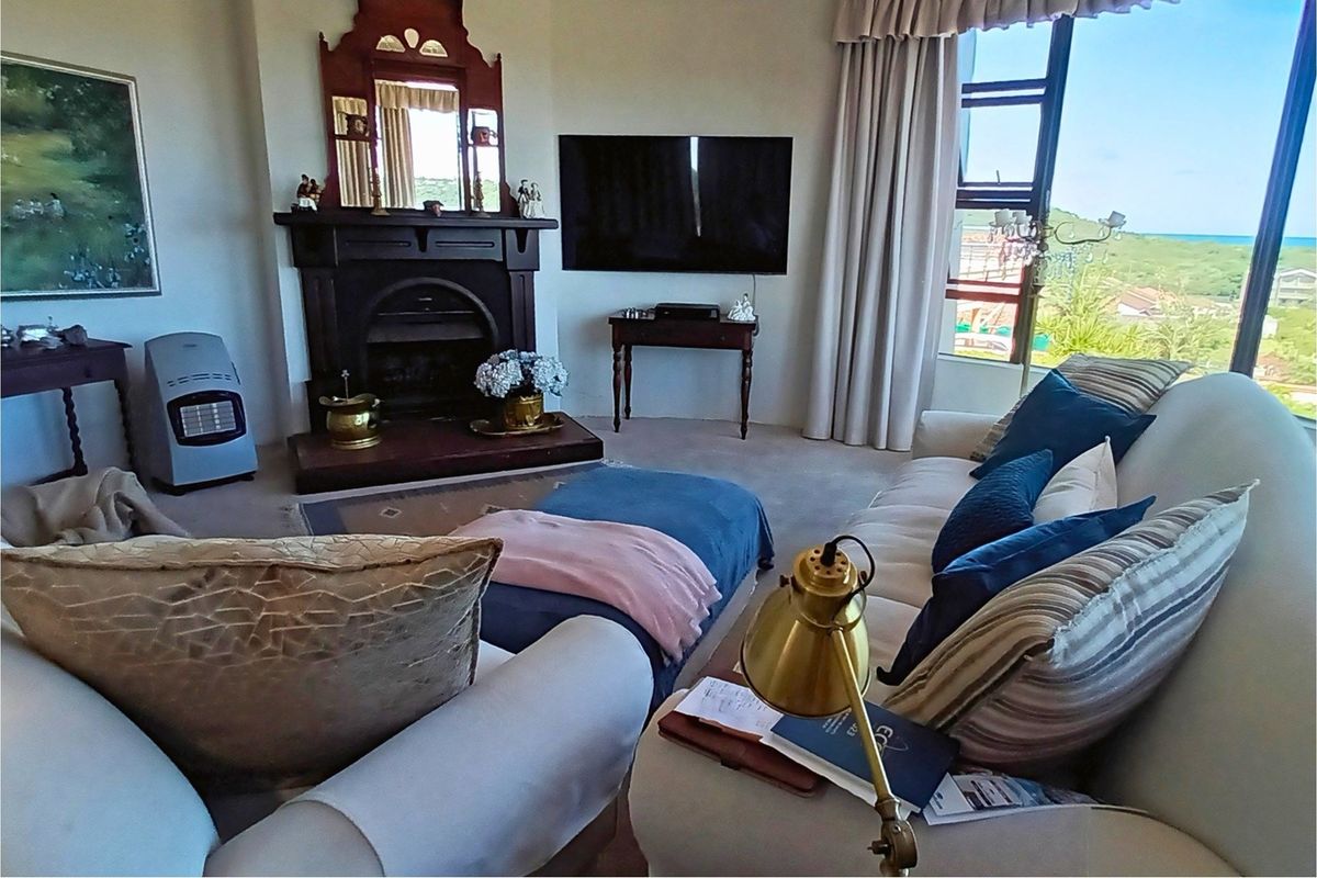 A comfortable living room featuring a traditional fireplace with a decorative mantelpiece and large windows offering scenic views.