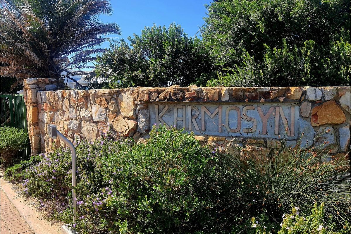 A stone boundary wall featuring the name Karmosyn, set within a landscaped garden area.