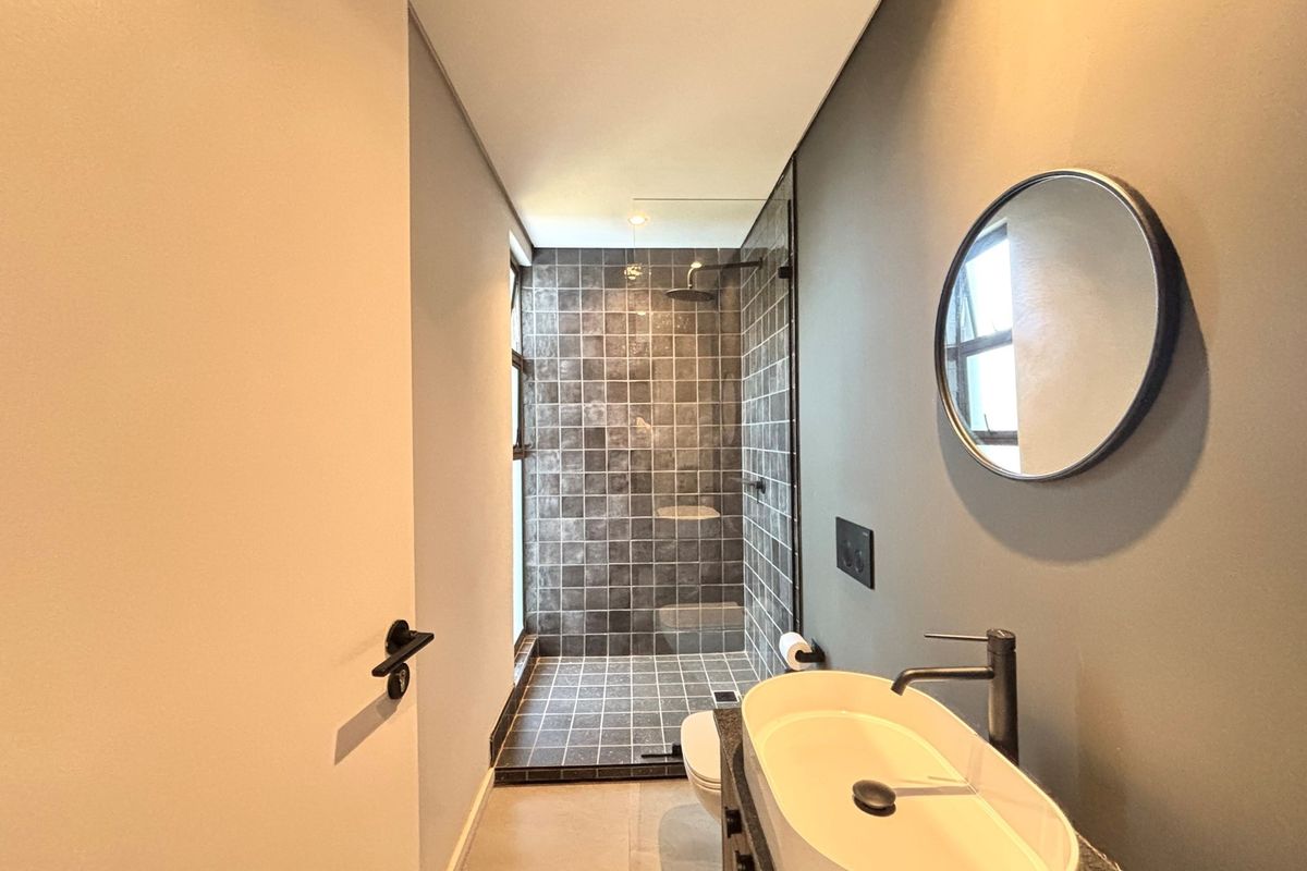Modern bathroom featuring a walk-in shower with dark tiled walls, a contemporary vessel sink, and sleek matte black fixtures.