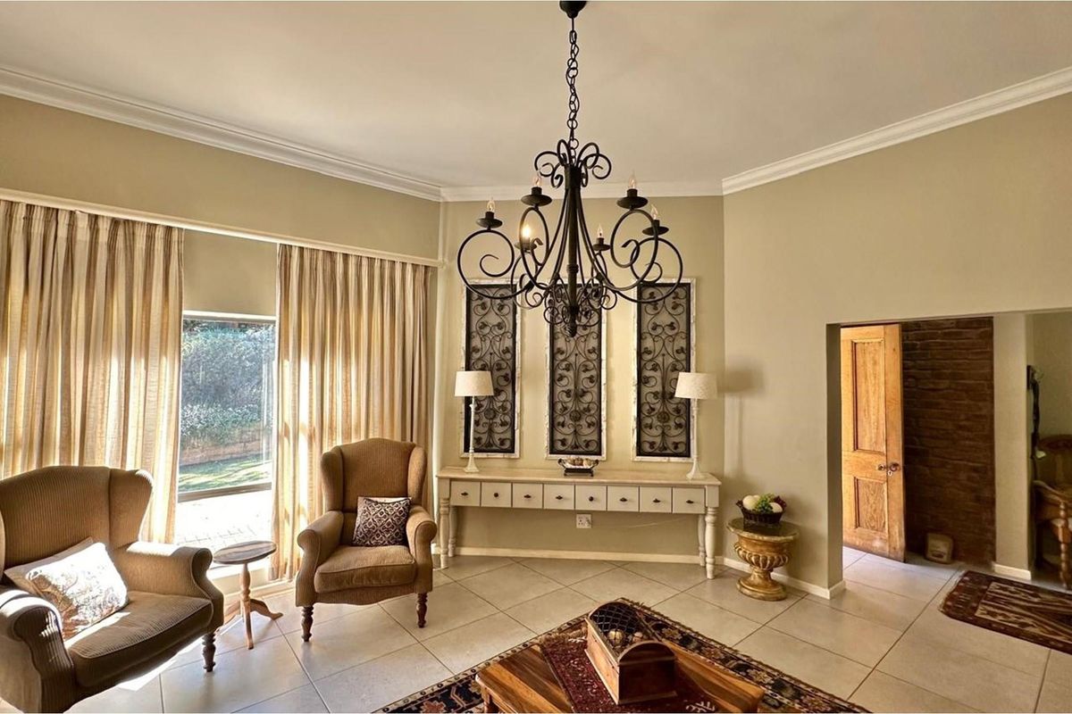 A well-lit living room featuring tiled flooring, crown molding, and a decorative wrought iron chandelier, providing a comfortable and inviting atmosphere.