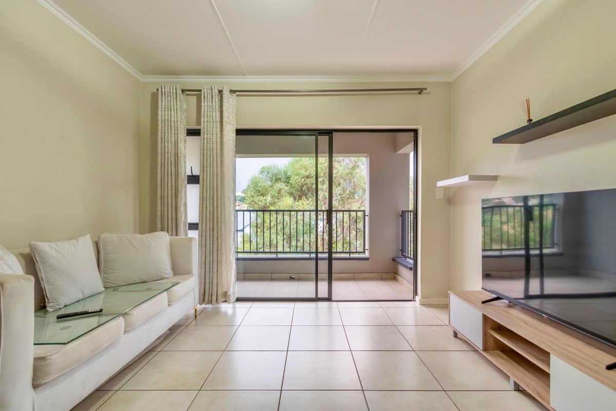 A bright living room featuring tiled flooring, built-in shelving, and large sliding glass doors that open onto a private balcony.
