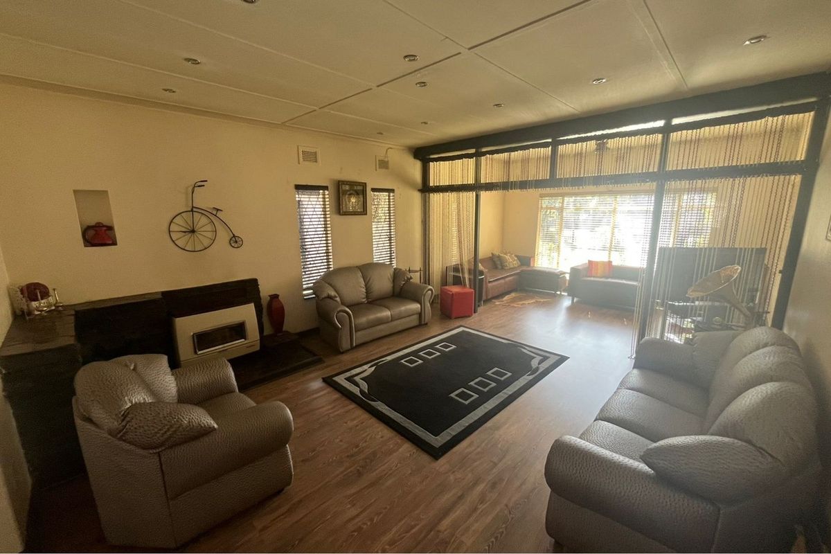 Spacious living room featuring laminate flooring, a built-in fireplace, and a large glass partition wall that separates the main area from an additional seating space.