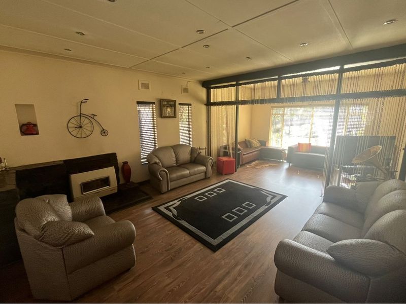 Spacious living room featuring laminate flooring, a built-in fireplace, and a large glass partition wall that separates the main area from an additional seating space.