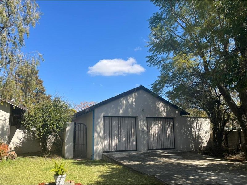 A detached double garage with a concrete driveway, set within a landscaped garden area.