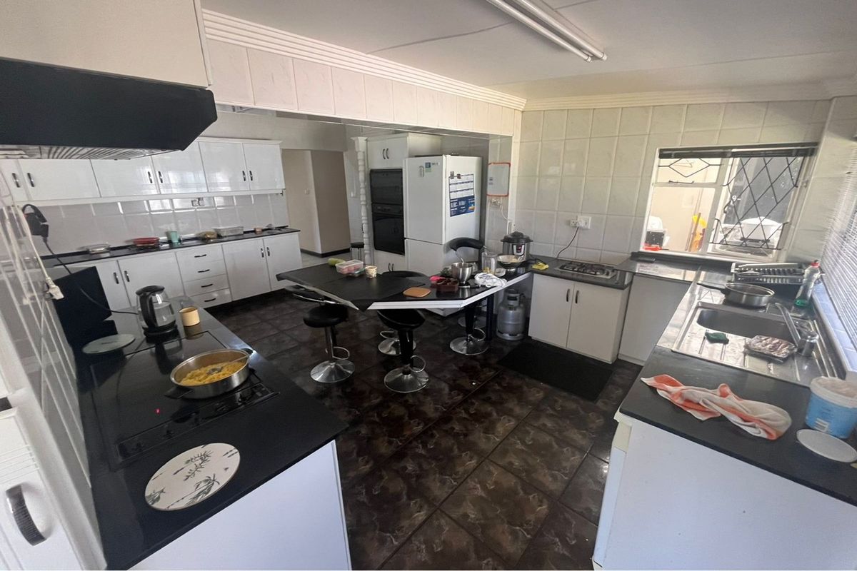 Spacious kitchen featuring extensive white cabinetry, black granite countertops, integrated double oven, and ceramic tile finishes throughout.