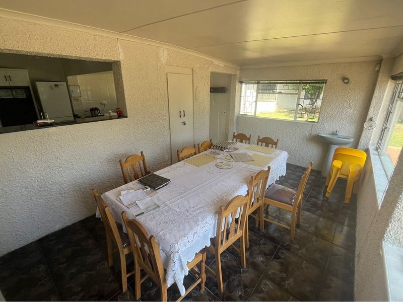 Dining area featuring tiled flooring, a built-in cupboard, and a convenient serving hatch connecting to the kitchen, with an integrated pedestal basin.