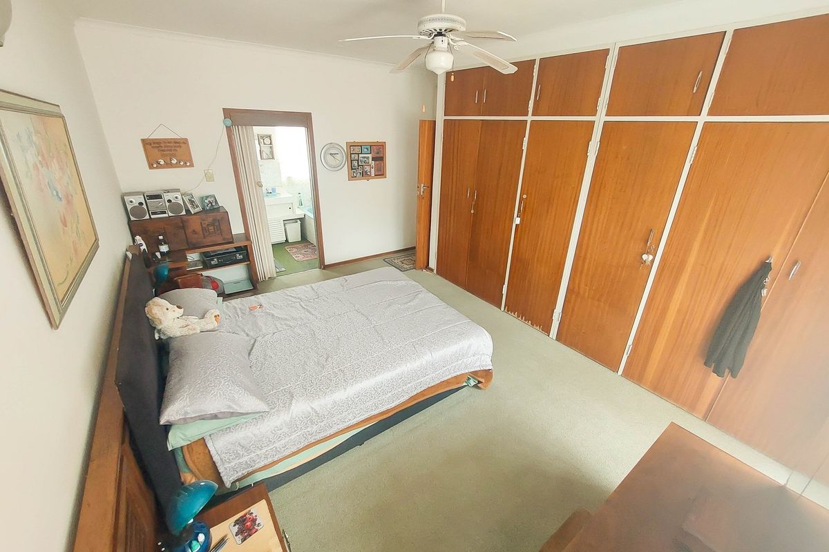 Spacious bedroom featuring extensive built-in wooden cabinetry, a ceiling fan, and direct access to an adjoining bathroom.