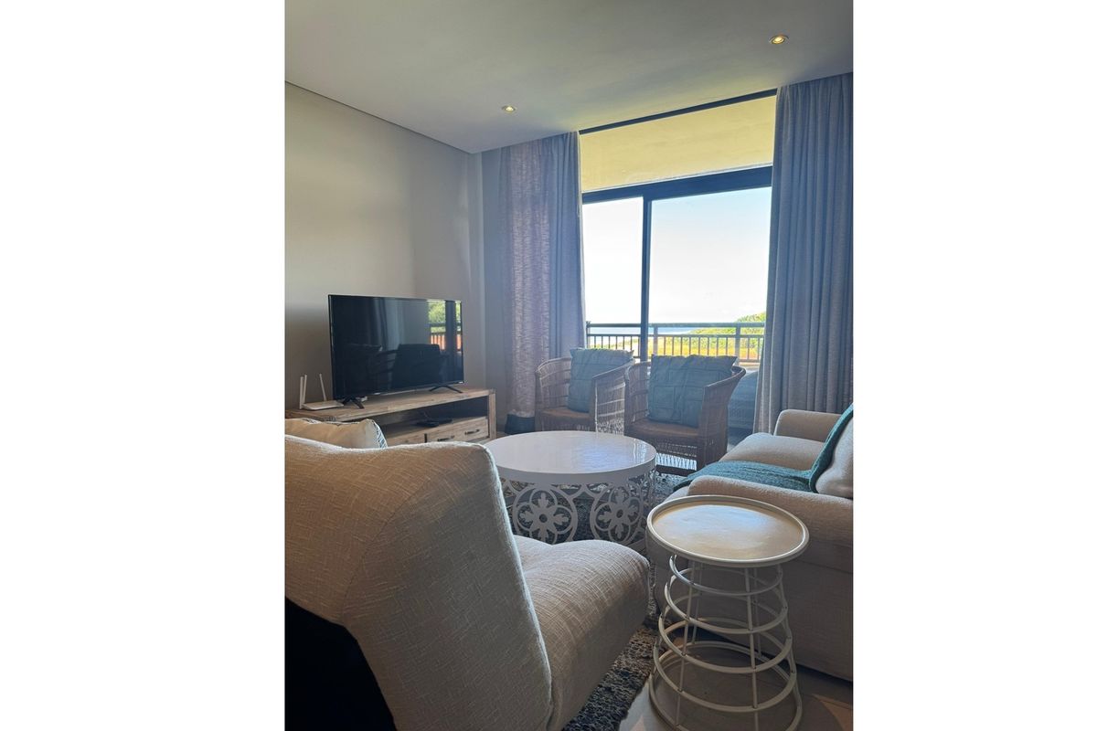 A bright living room featuring large sliding glass doors that open onto a balcony, providing natural light and outdoor access.