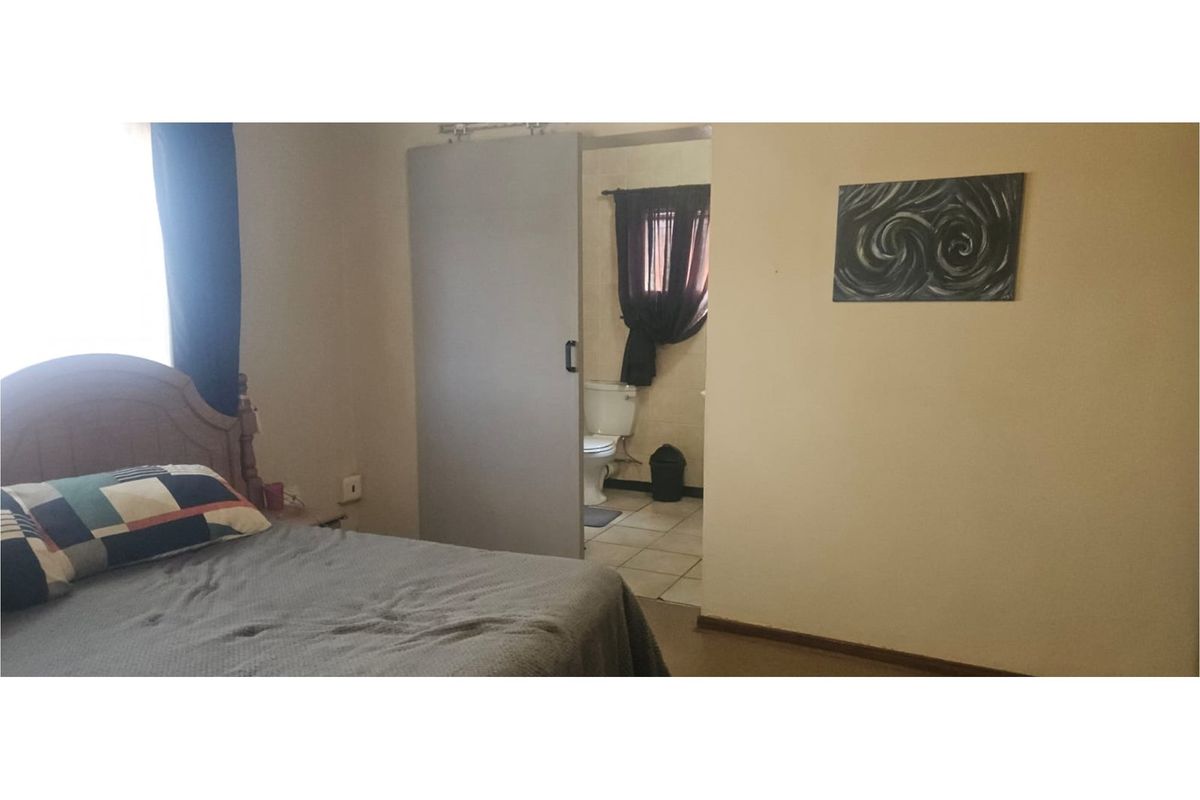 A bedroom featuring a sliding door leading to an en-suite bathroom with tiled flooring.