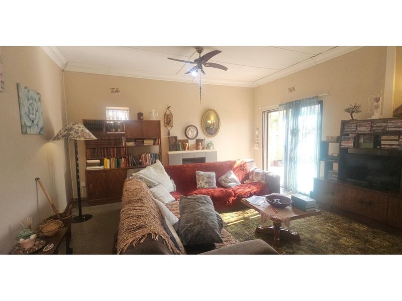 A comfortable living room featuring a ceiling fan and sliding glass doors that provide access to the outdoor area.