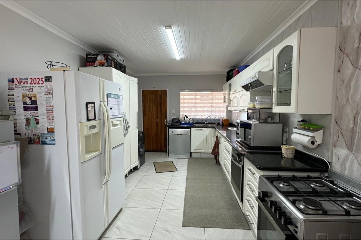 A functional kitchen featuring white cabinetry, granite countertops, a gas stove, and tiled flooring with a classic tongue and groove ceiling finish.