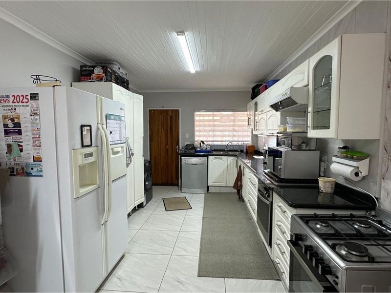 A functional kitchen featuring white cabinetry, granite countertops, a gas stove, and tiled flooring with a classic tongue and groove ceiling finish.
