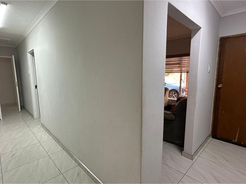 A clean, tiled hallway providing access to multiple rooms, featuring neutral walls and functional overhead lighting.