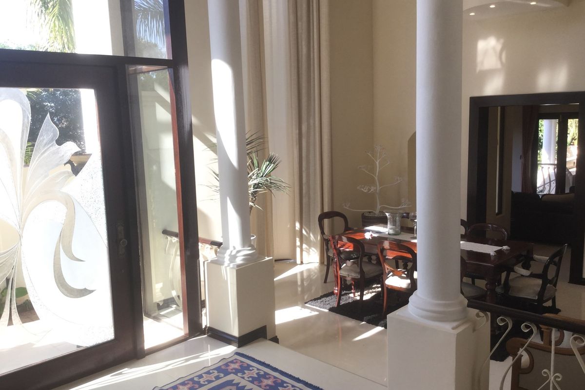 Spacious living area featuring high ceilings, decorative columns, and large glass doors that provide ample natural light and access to the exterior.