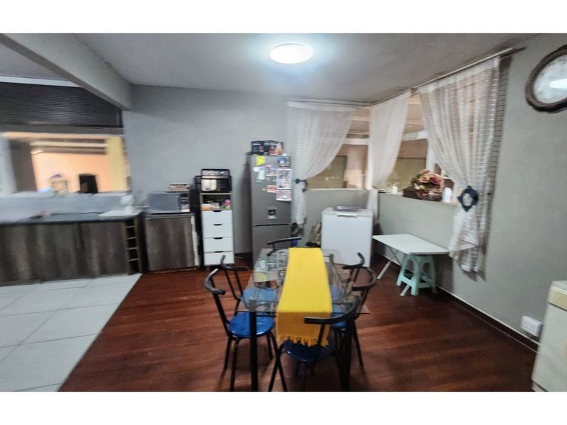 Open plan living and kitchen area featuring laminate flooring, tiled kitchen section, and built-in cabinetry.