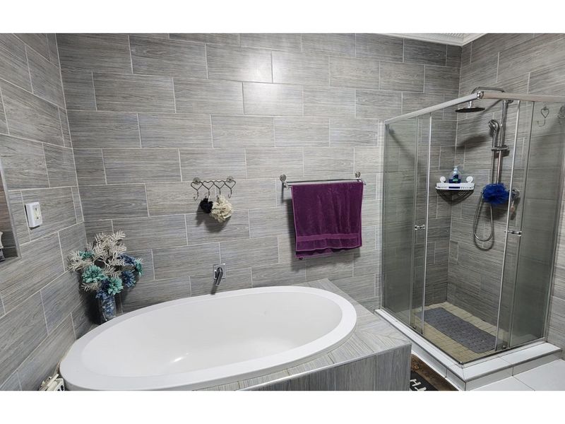 Modern bathroom featuring a built-in bathtub, a separate glass-enclosed shower, and contemporary grey wood-look wall tiling.