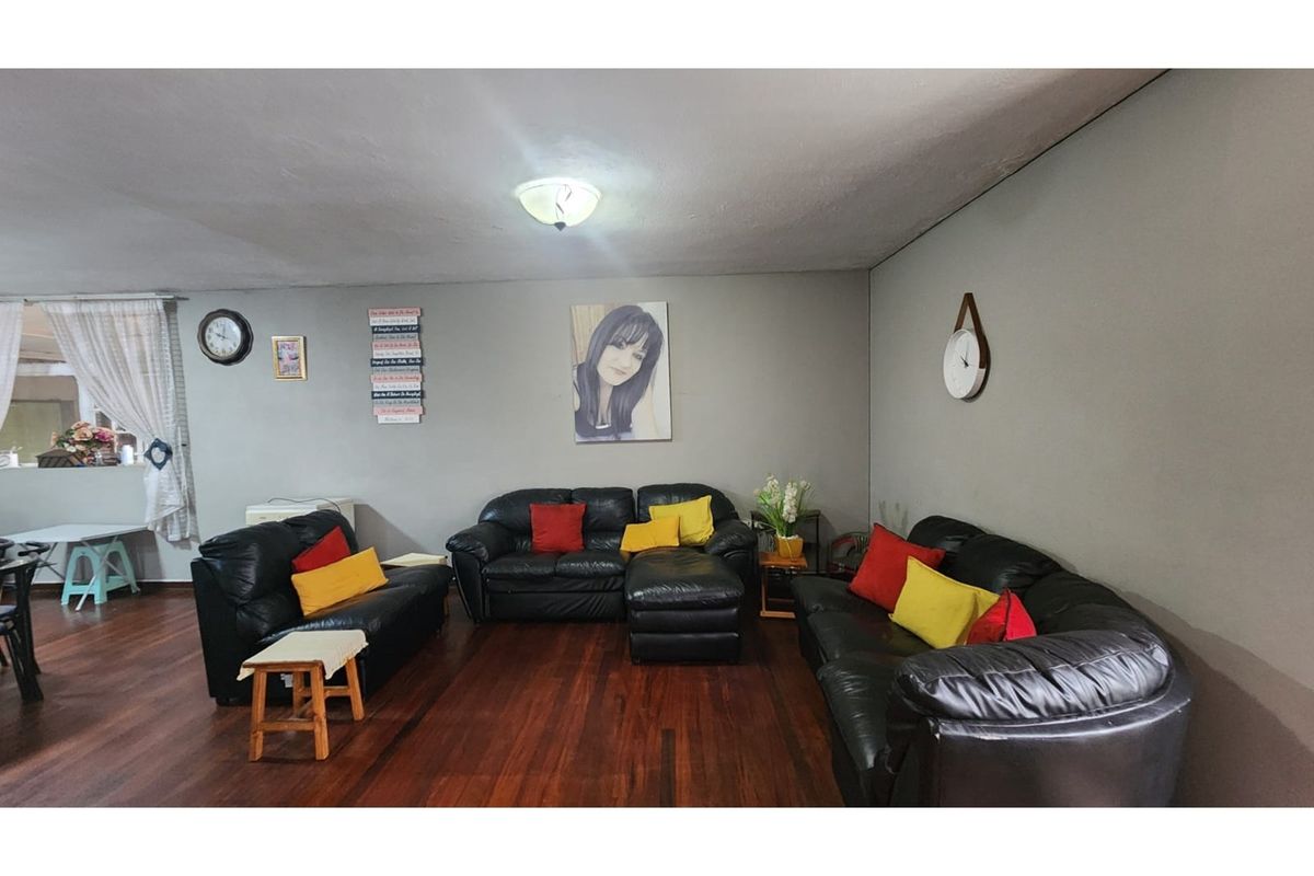 A spacious living room featuring dark hardwood flooring and neutral wall tones, providing a comfortable and versatile area for relaxation.