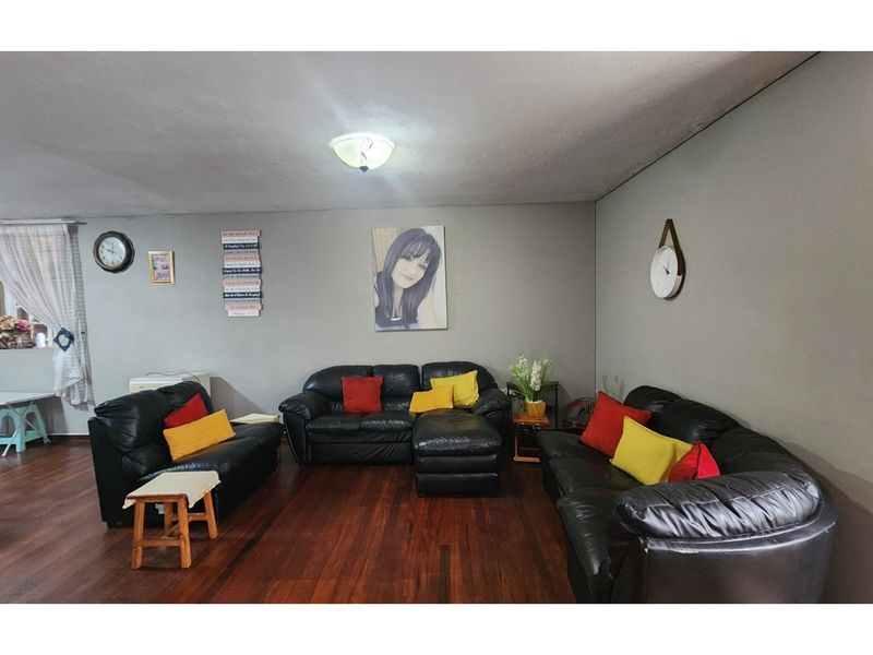 A spacious living room featuring dark hardwood flooring and neutral wall tones, providing a comfortable and versatile area for relaxation.