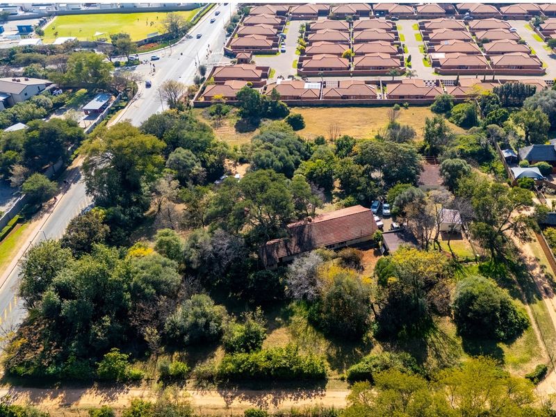 Aerial view of a residential vacant land plot featuring mature trees, established vegetation, and an existing dwelling structure.