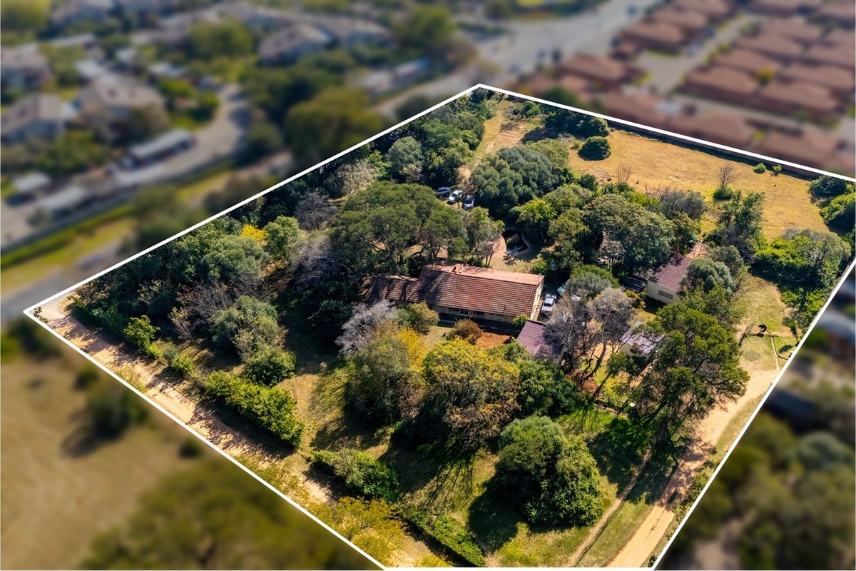 Aerial view of a large residential vacant land plot featuring mature trees, established vegetation, and existing structures on the property.