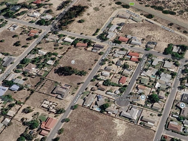 An aerial view of a vacant residential plot situated within a developed neighborhood, offering convenient street access and proximity to local amenities.