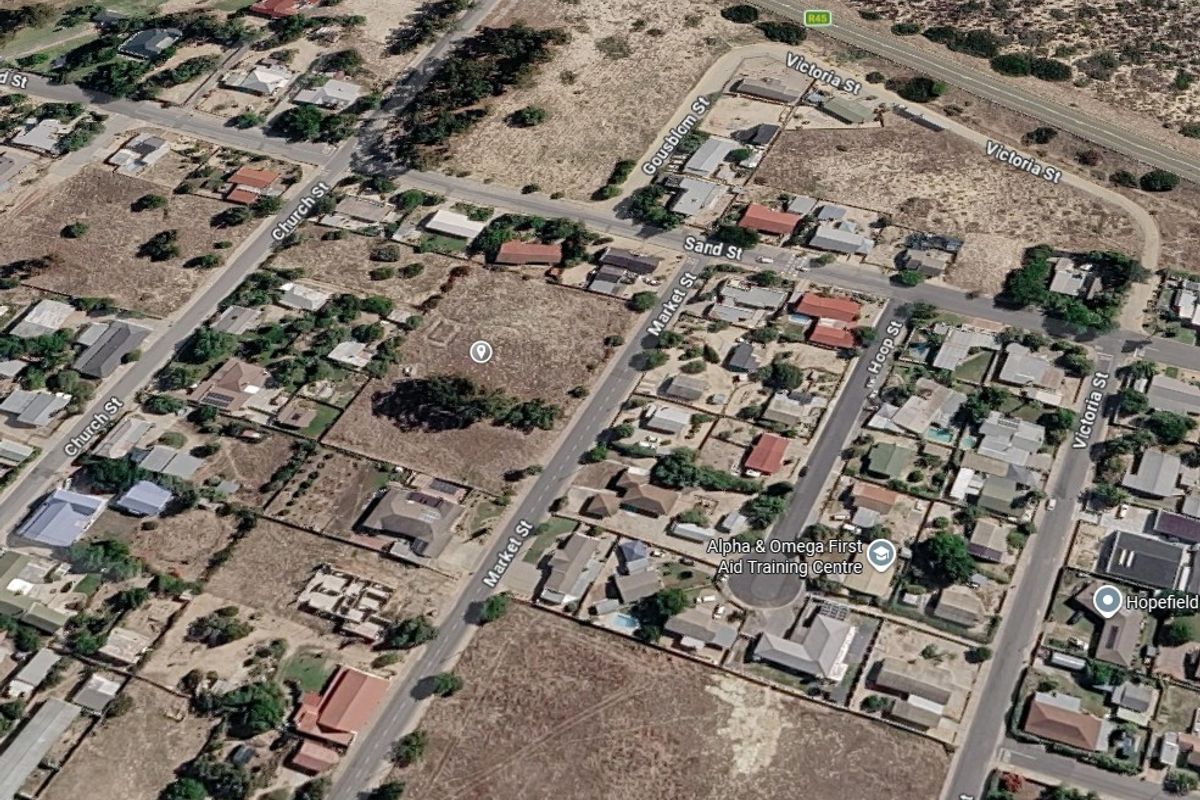 An aerial view of a vacant residential plot situated within a developed neighborhood, offering convenient street access and proximity to local amenities.