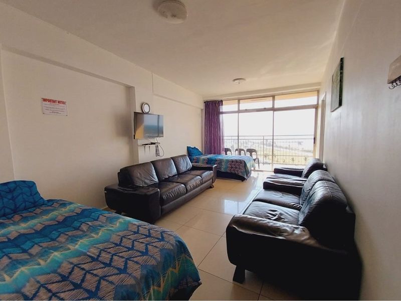 Open-plan living area featuring large sliding glass doors leading to a balcony, tiled flooring, and neutral wall finishes.