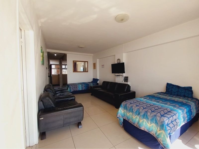 A spacious open-plan living area featuring tiled flooring and neutral walls, providing a versatile layout suitable for combined living and sleeping arrangements.