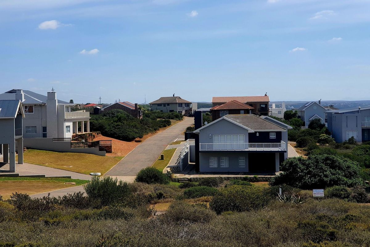 An elevated view of a residential neighbourhood featuring paved roads, established homes, and natural coastal vegetation.