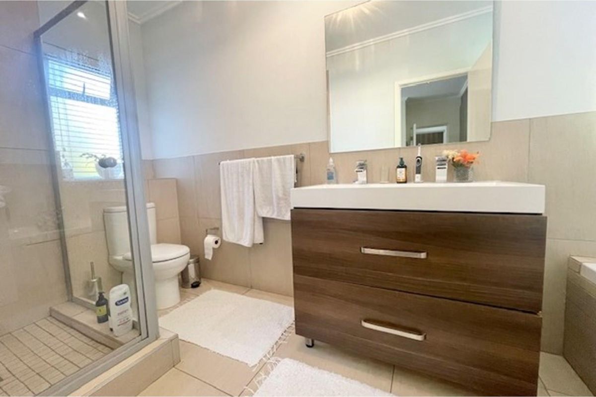 A modern bathroom featuring a glass-enclosed shower, a contemporary vanity with double basins, and neutral wall tiling.