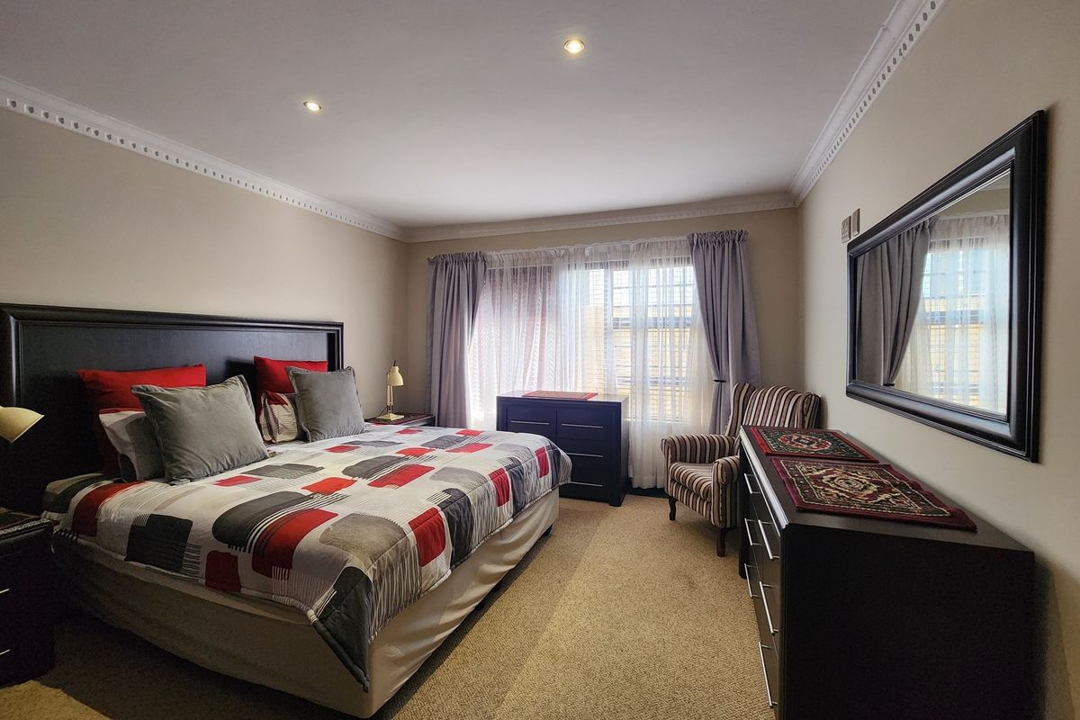 A well-maintained bedroom featuring neutral wall tones, decorative crown molding, recessed ceiling lighting, and fitted carpeting.