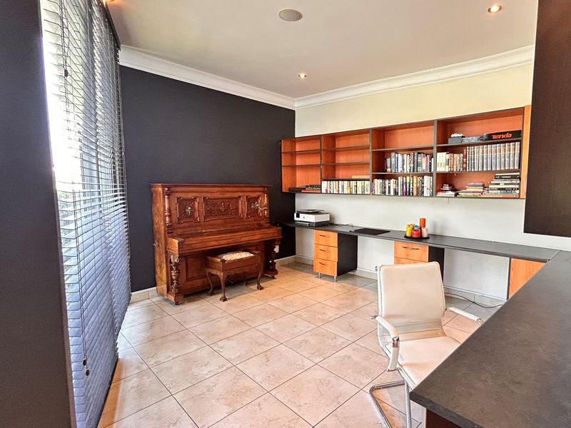 A functional home office featuring built-in shelving, a long desk workspace, tiled flooring, and recessed ceiling lighting.