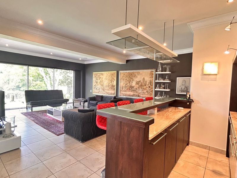 Spacious open-plan living area featuring a built-in bar with stone countertop, recessed lighting, and large sliding glass doors leading to the outdoor space.