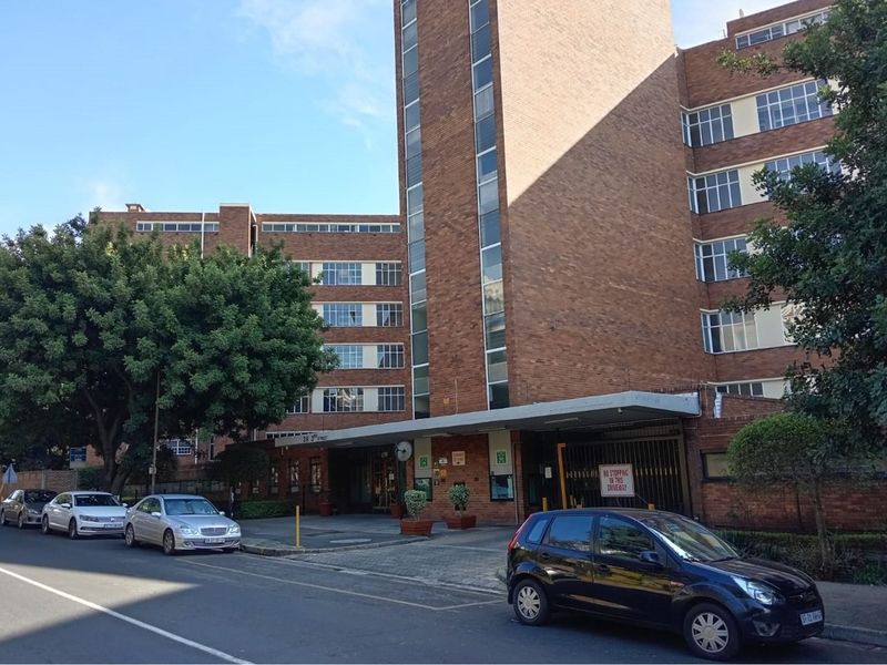 Front elevation of a multi-story brick apartment building featuring a covered entrance area and secure gated access.