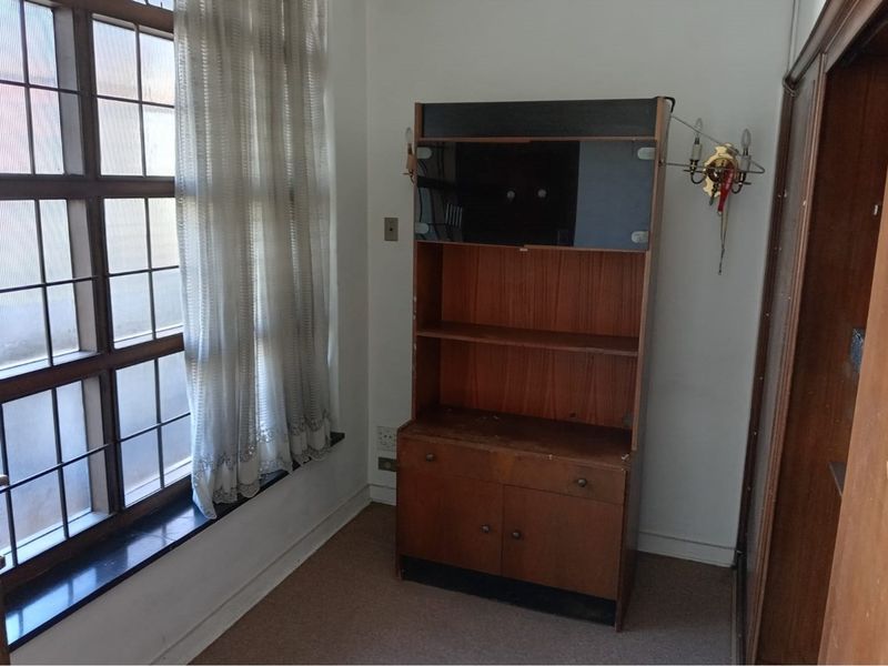 A bedroom featuring a grid-pattern window and built-in wardrobe, requiring cosmetic updates to modernize the space.