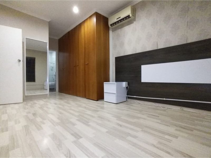 A bedroom featuring light laminate flooring, a large built-in wooden wardrobe, a wall-mounted headboard feature, and a split-system air conditioning unit.