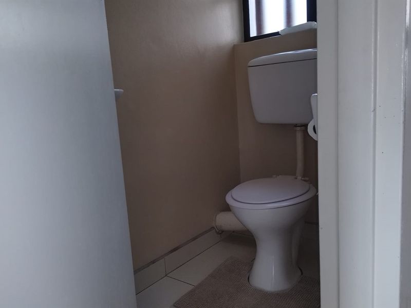 A compact, functional bathroom featuring a standard toilet and tiled flooring.