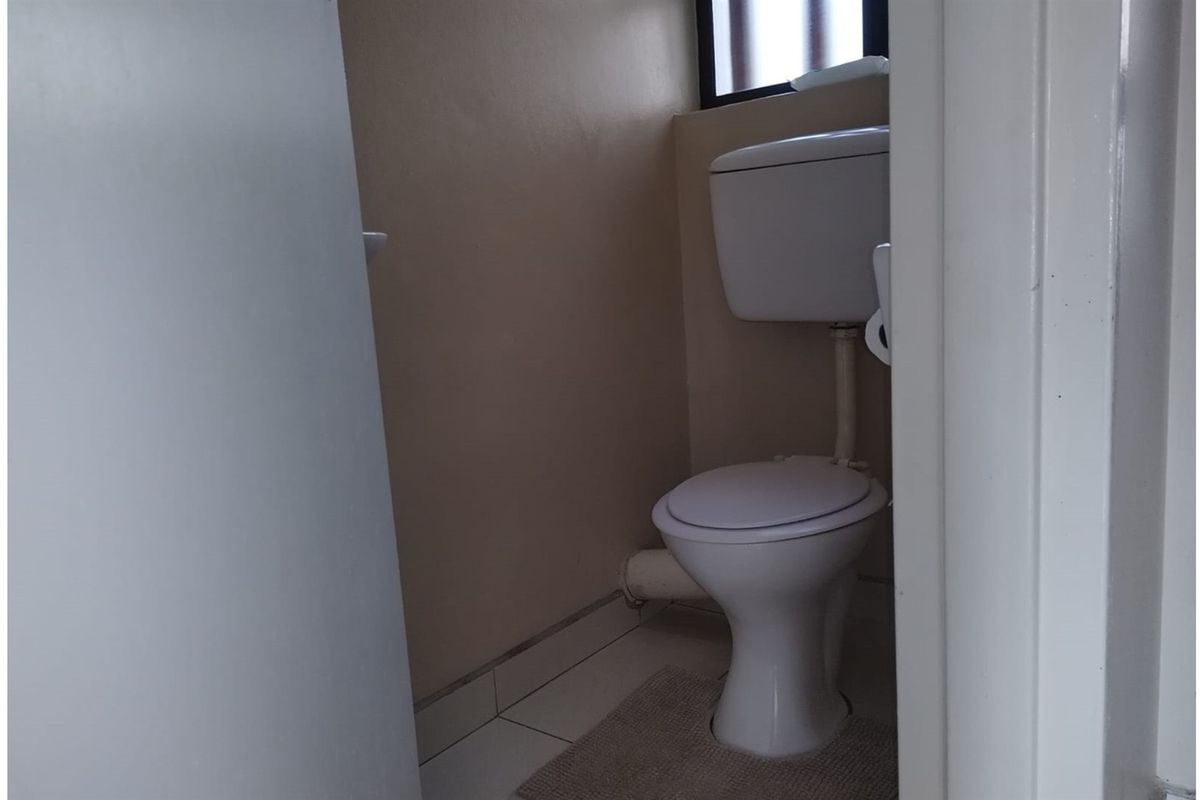 A compact, functional bathroom featuring a standard toilet and tiled flooring.