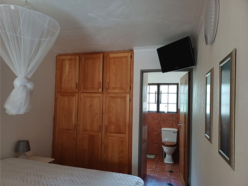 Bedroom featuring built-in wooden cupboards and direct access to an en-suite bathroom with tiled flooring.