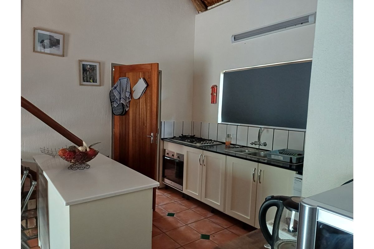 A functional kitchen featuring built-in cabinetry, a gas hob, an integrated oven, and a tiled backsplash with terracotta flooring.