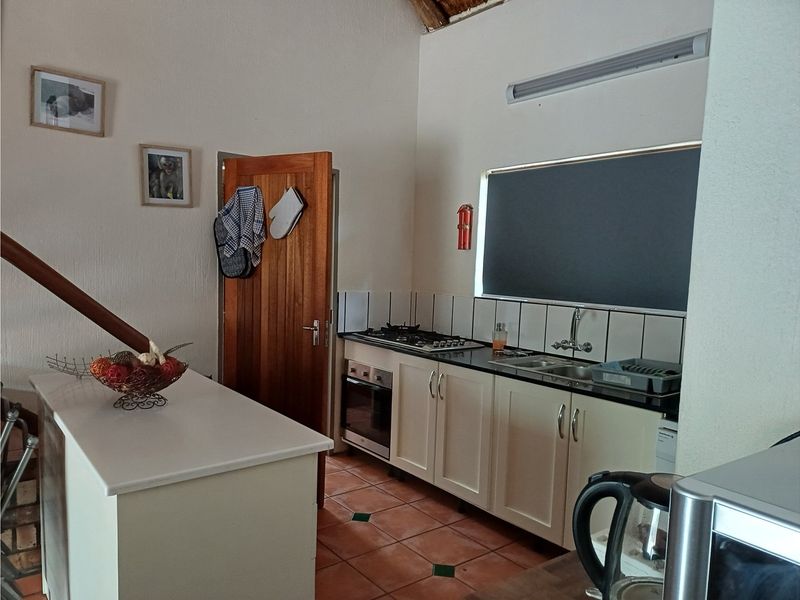 A functional kitchen featuring built-in cabinetry, a gas hob, an integrated oven, and a tiled backsplash with terracotta flooring.