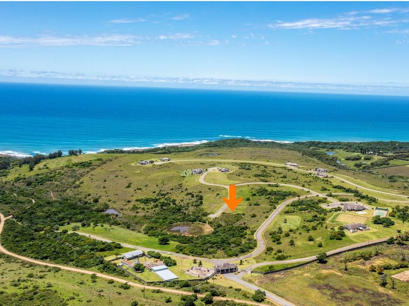 Aerial view of a vacant residential plot situated in a coastal estate, featuring scenic ocean views and established road access.